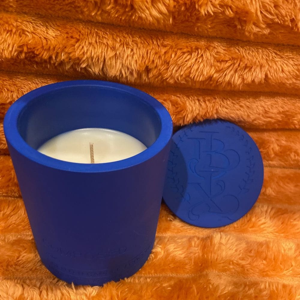 Blue candle holder with a white candle inside and its lid beside it.